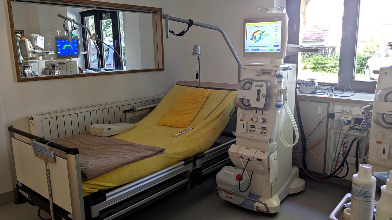 Im Dialysezentrum steht für jeden Patienten das eigene Dialysegerät zur Behandlung direkt am Bett Ein betriebsbereites Dialysegerät steht seitlich am leeren Patientenbett in einem Dialysezentrum
