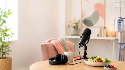 Podcast-Mikrofon, Kopfhörer und eine Mahlzeit in einem hellen Raum mit dezentem Dialysegerät im Hintergrund