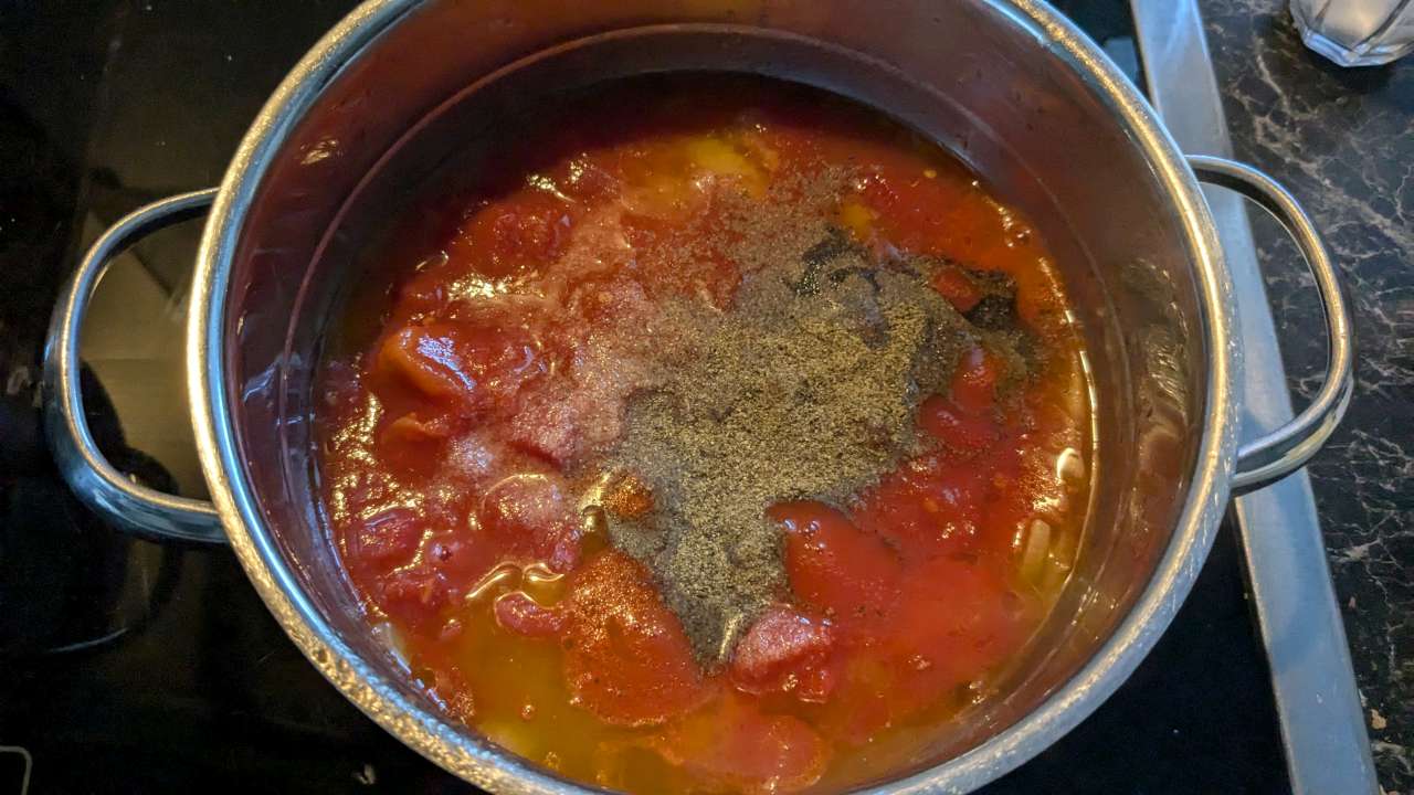 Tomatenstücke, Pfeffer, Salz und Zucker kommen in den Topf mit Olivenöl