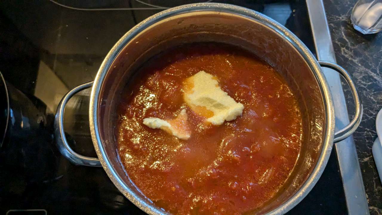 Stück Butter wird der Tomatensoße in einem Topf zugegeben