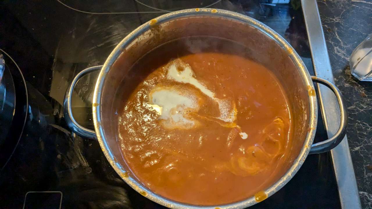 Die Sahne wird in den Topf mit der Tomatensoße zugegeben