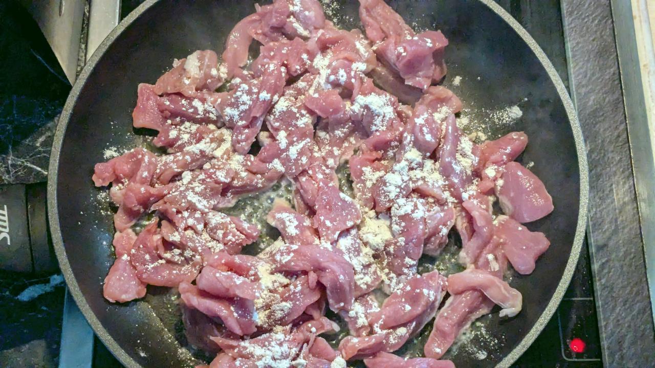 Frische Streifen Schweinegeschnetzeltes mit Mehl bestäubt in einer Pfanne