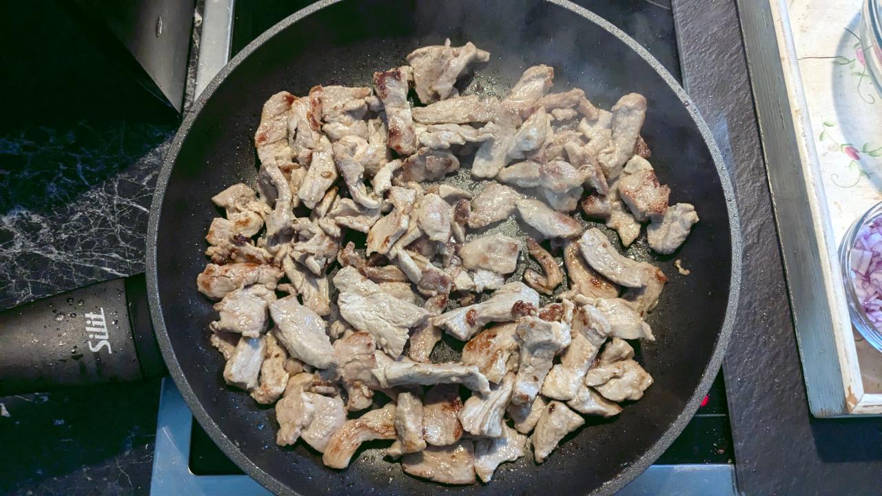 Angebratene Streifen Schweinegeschnetzeltes in einer Pfanne